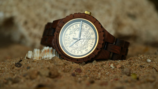 Wooden watch with detailed face on a sandy surface